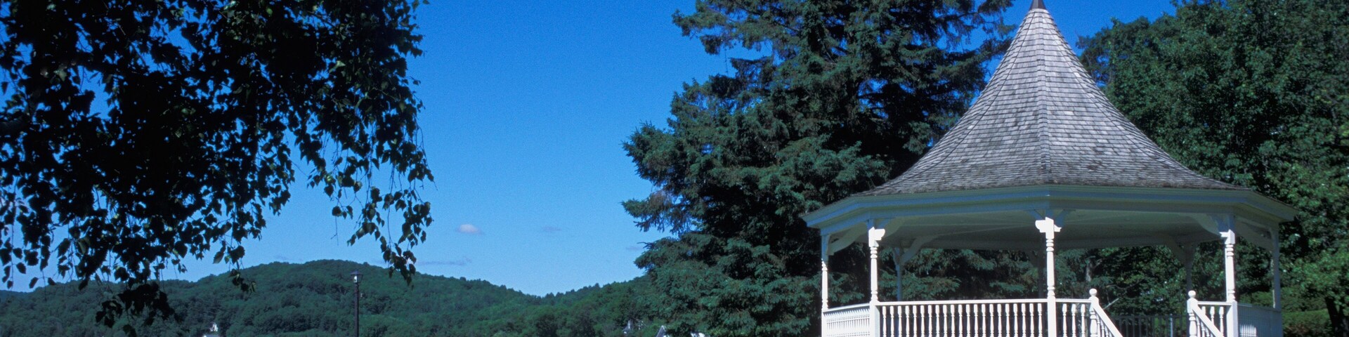 A gazebo by a lake with a clear blue sky.