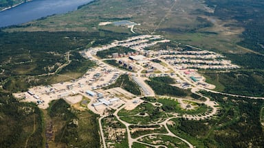 An aerial view of a large industrial complex with multiple buildings and roads, surrounded by dense forests and a lake.