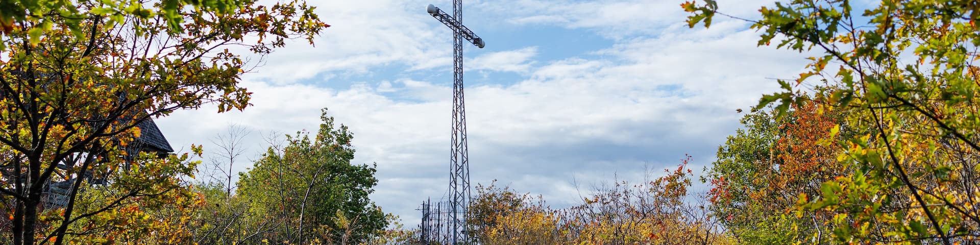 Low angle view of a large cross surrounded by trees