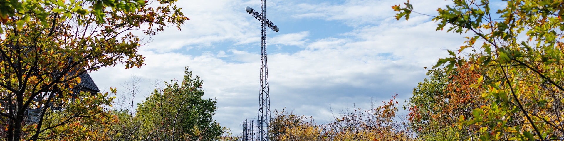 Low angle view of a large cross surrounded by trees