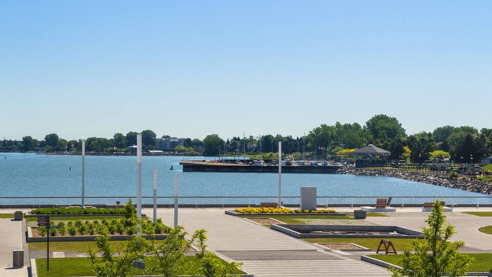 A waterfront promenade with a clear view of the water, a dock, and a gazebo.