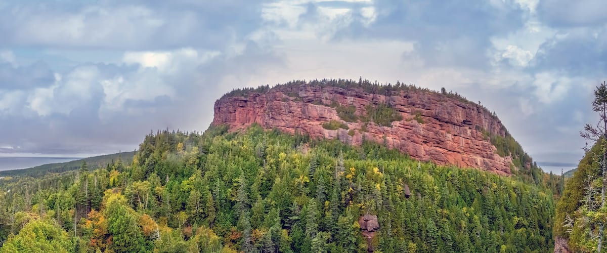 A rocky mountain peak surrounded by dense forest.