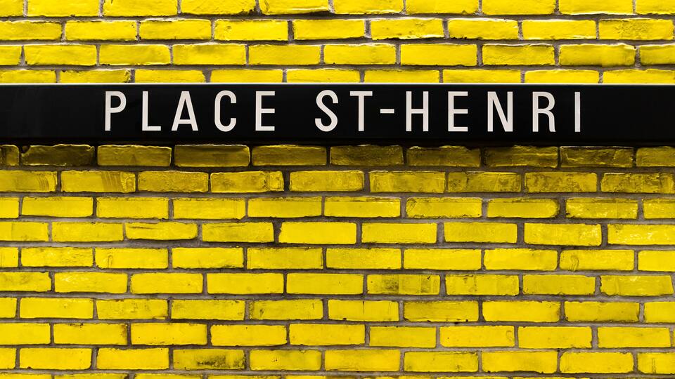 A yellow brick wall with a black sign reading "PLACE ST-HENRI".