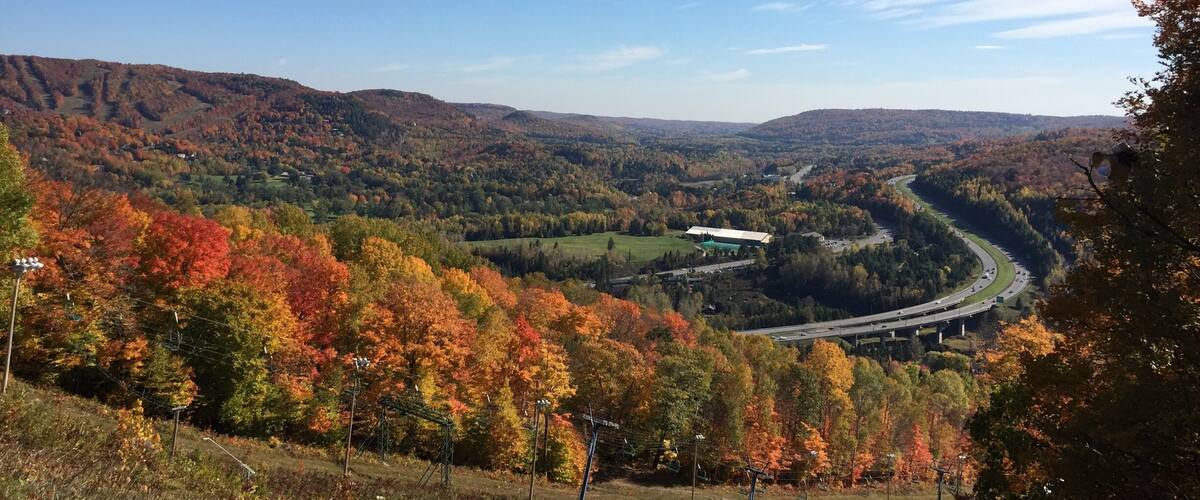 A valley with autumn foliage, a winding river, and a highway.
