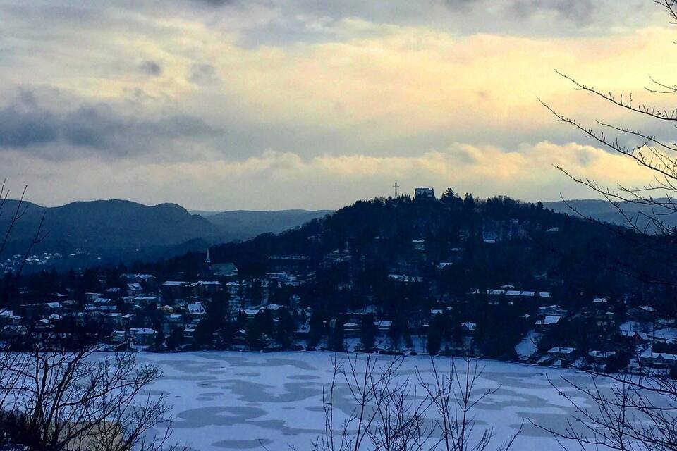 A snowy landscape with a town nestled in the valley, surrounded by hills and a frozen lake.