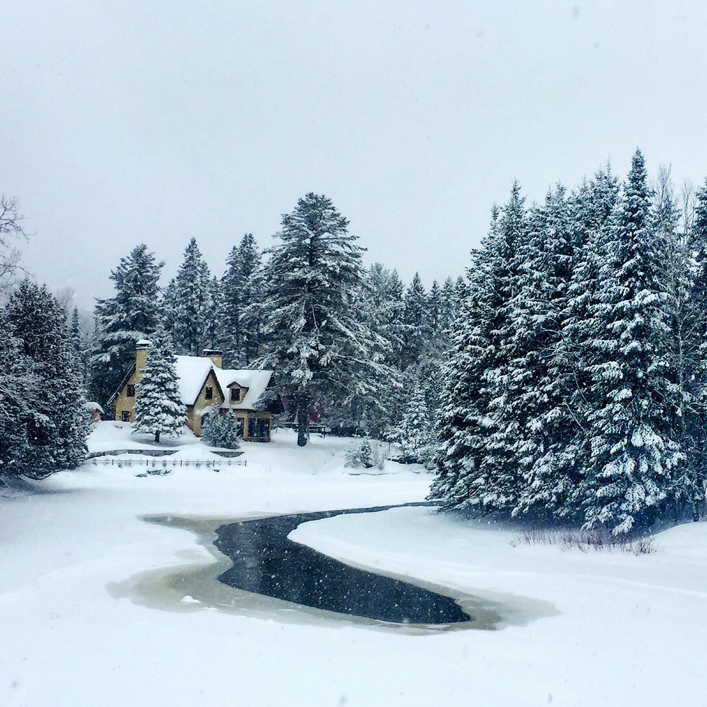 A snow-covered landscape with a house and a frozen river.