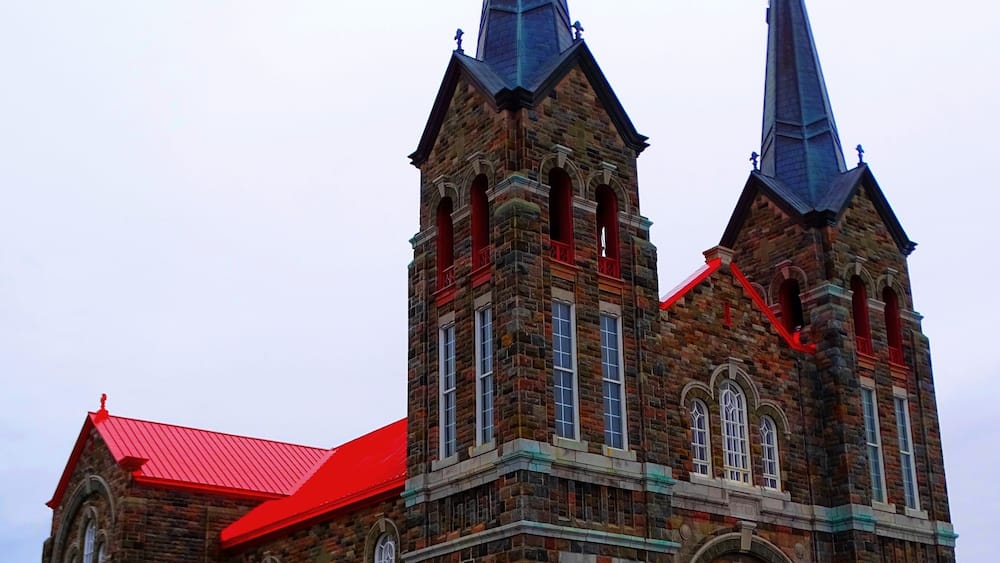 A large brick church with two spires and a red roof.