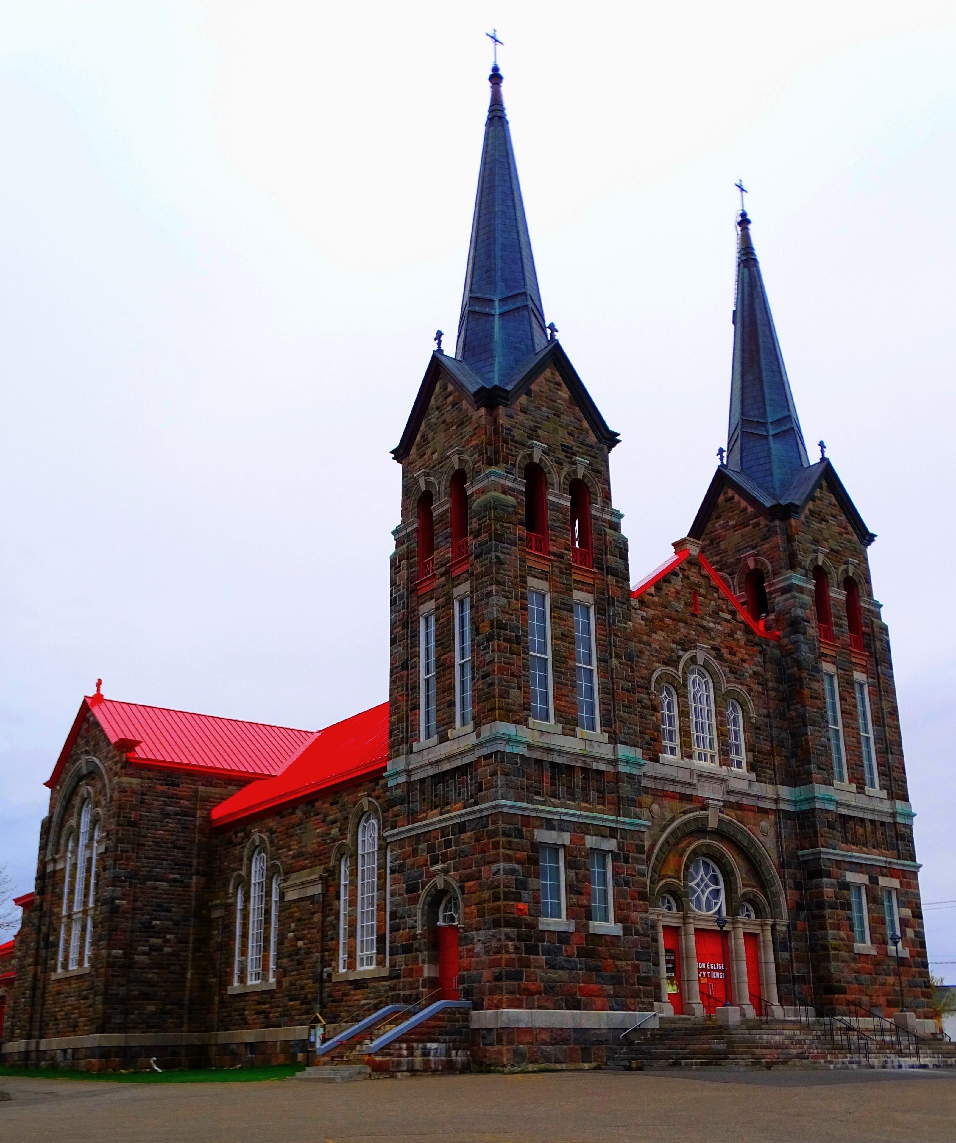 A large brick church with two spires and a red roof.