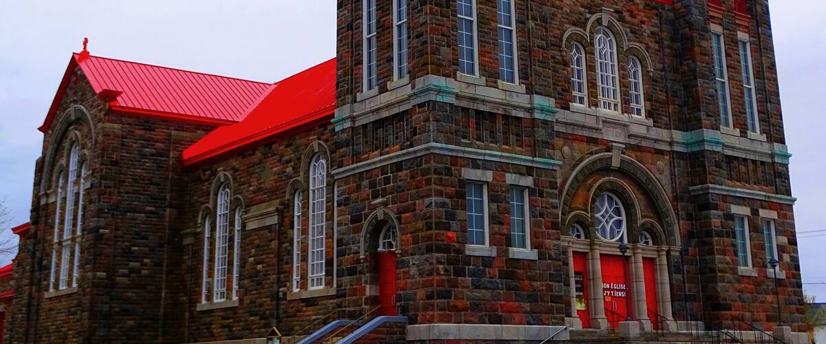 A large brick church with two spires and a red roof.