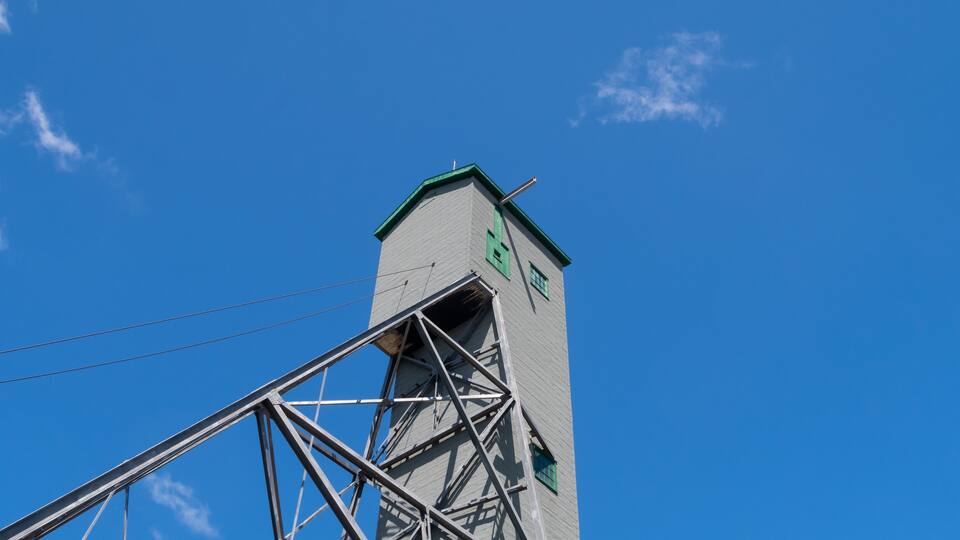 A tall building with a green roof and a metal framework.