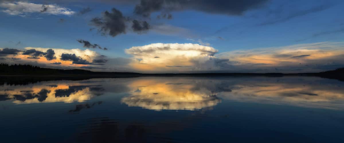 A calm lake reflecting the sky with clouds.