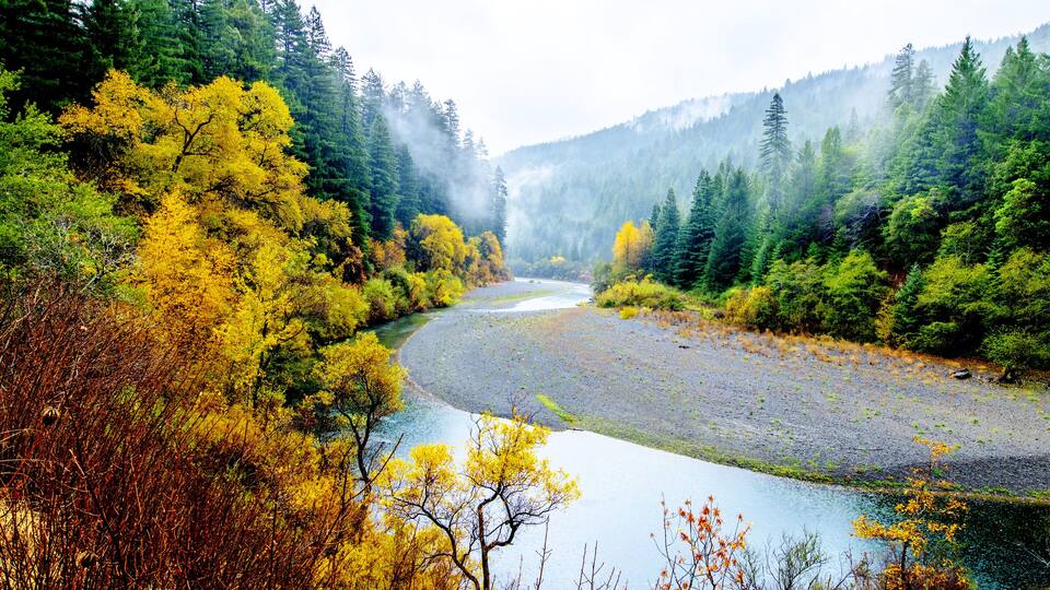 A river winding through a forested valley with autumn foliage.