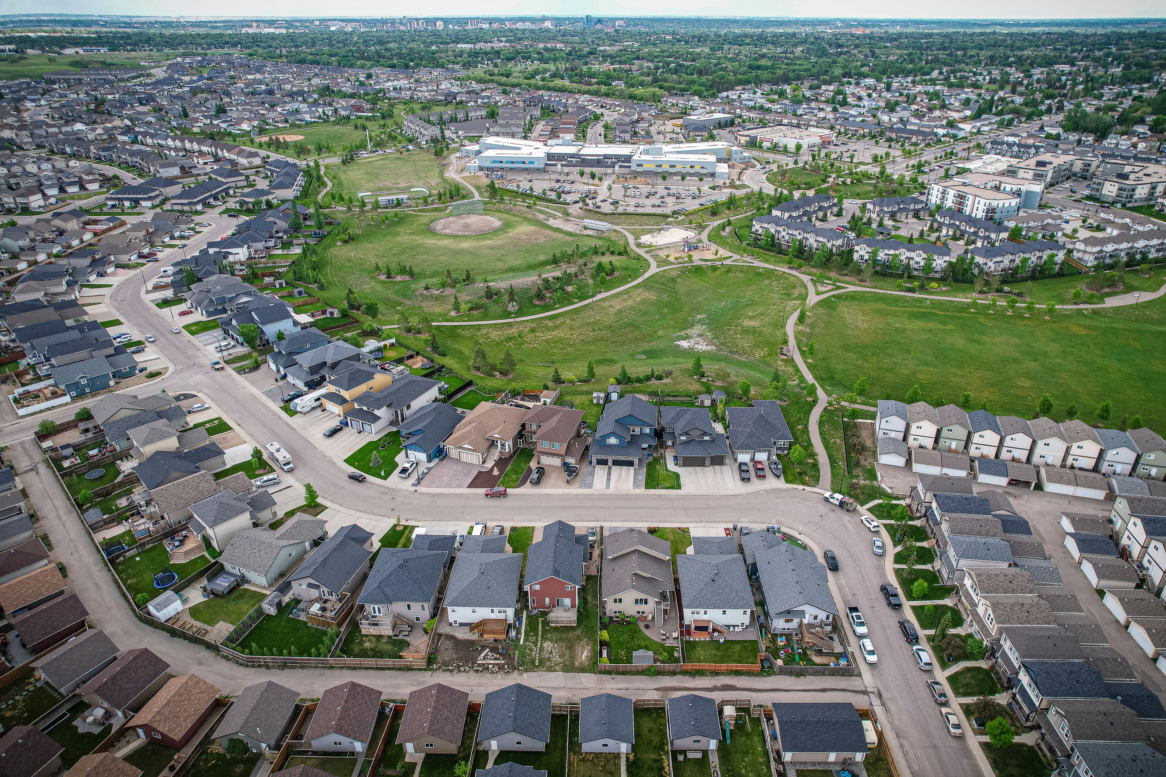 An aerial view of a residential area with houses, roads, and a large building complex.