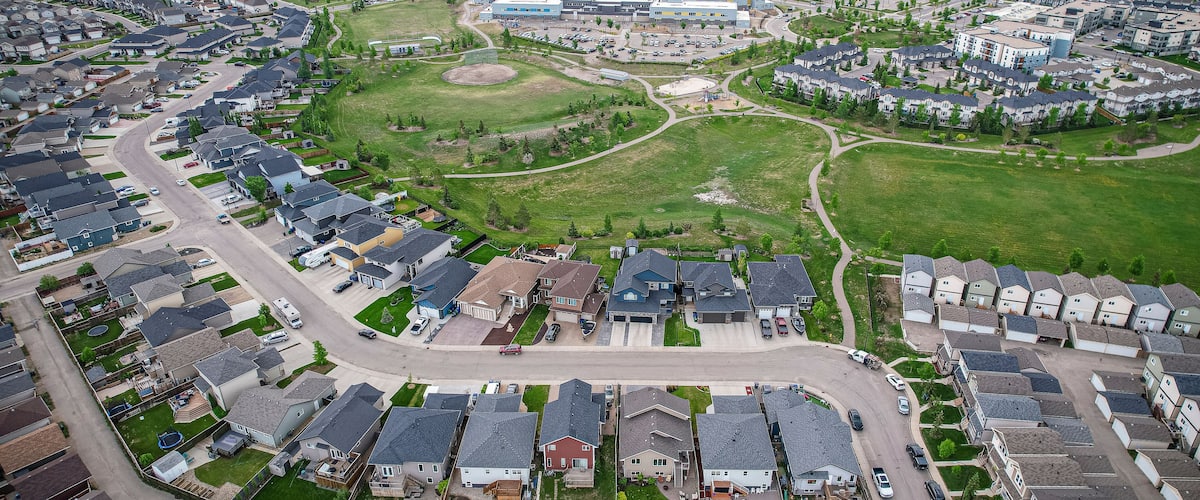 An aerial view of a residential area with houses, roads, and a large building complex.