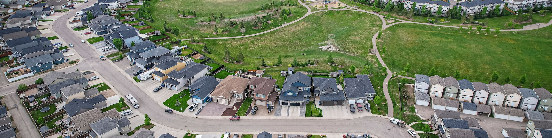 An aerial view of a residential area with houses, roads, and a large building complex.