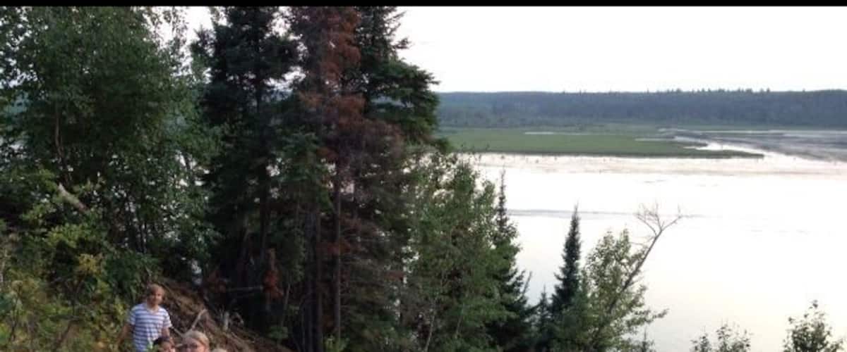 A group of people hiking near a lake surrounded by dense forest.