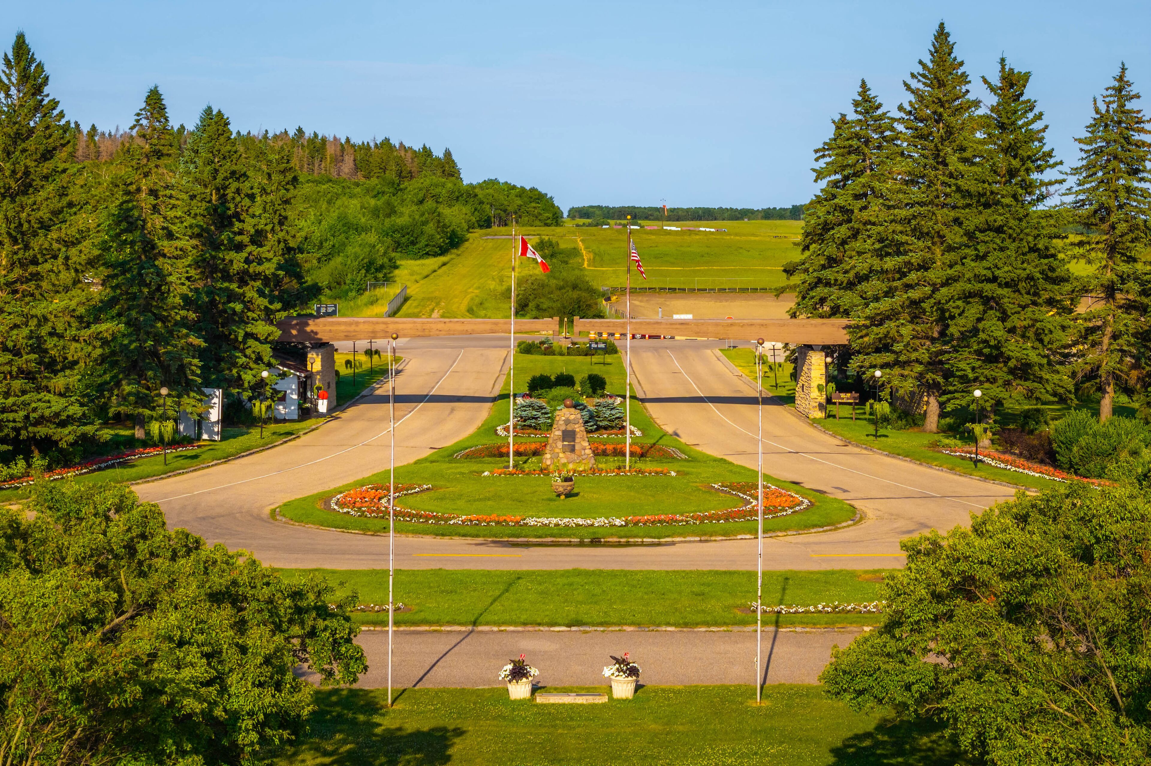 A landscaped intersection with a central fountain, surrounded by trees and a grassy hill in the background.