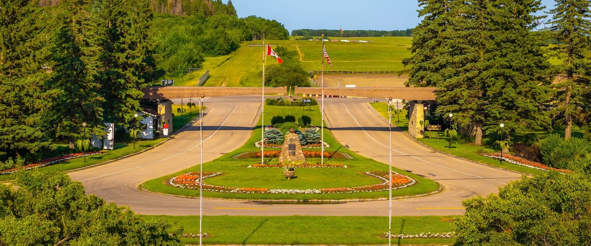 A landscaped intersection with a central fountain, surrounded by trees and a grassy hill in the background.