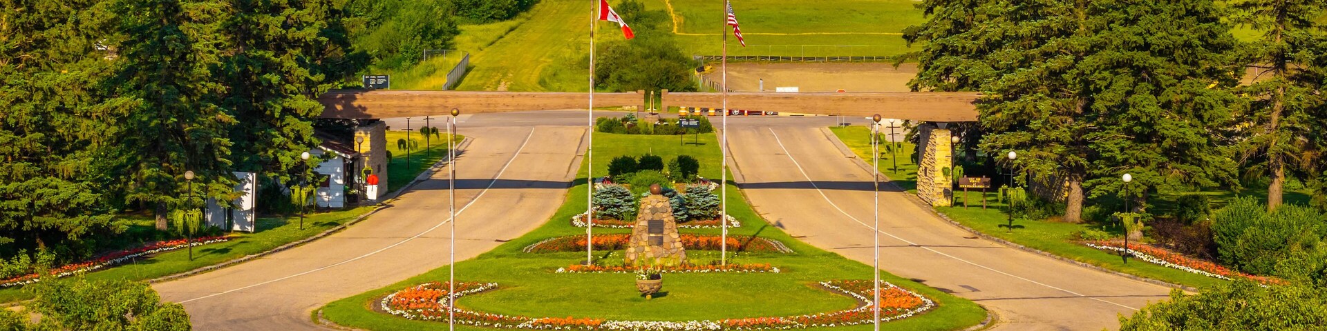 A landscaped intersection with a central fountain, surrounded by trees and a grassy hill in the background.