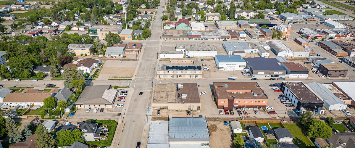 An aerial view of a small town with a central street, various buildings, and surrounding greenery.