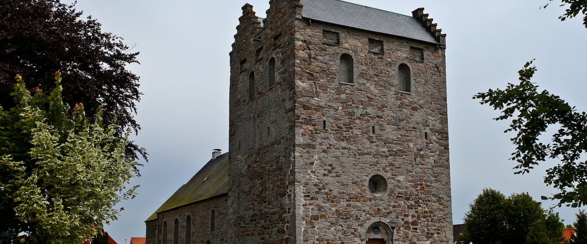 A historic stone church with a tall tower and arched windows.