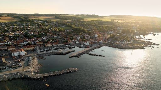 Golden Hour Aerial View of Allinge Harbor and Coastal Town on Bornholm Island with Sunlight Reflecting on Calm Sea