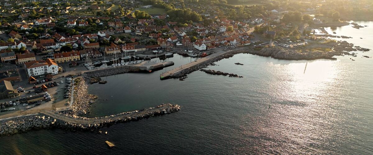A coastal town with a marina, houses, and surrounding greenery.