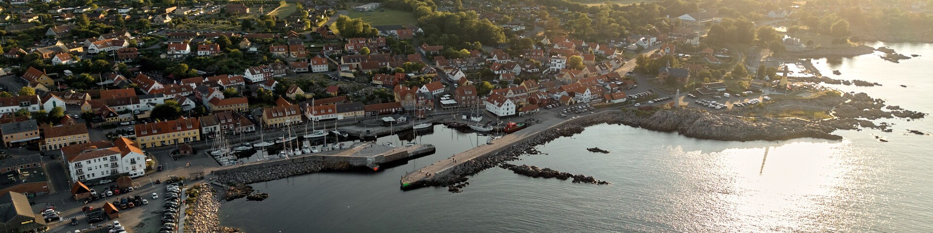 A coastal town with a marina, houses, and surrounding greenery.