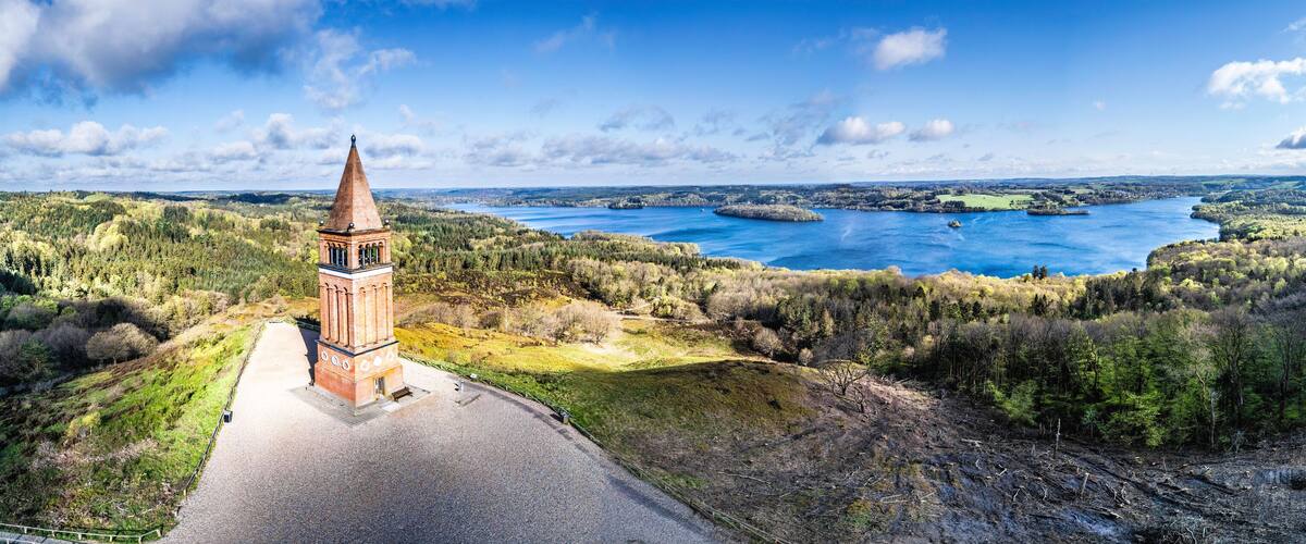 A tower, a lake, and forested hills.