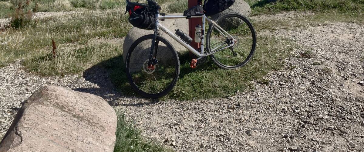 A bicycle parked on a gravel path with a view of the ocean in the background.