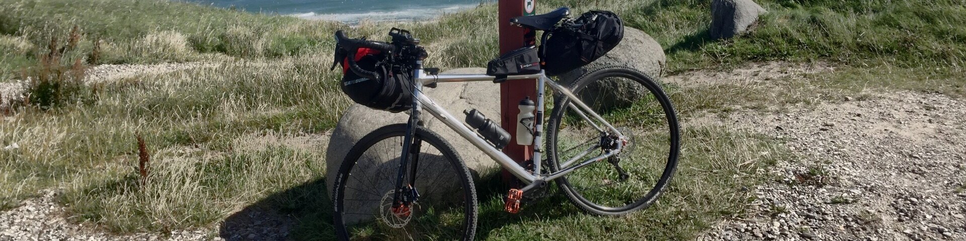 A bicycle parked on a gravel path with a view of the ocean in the background.