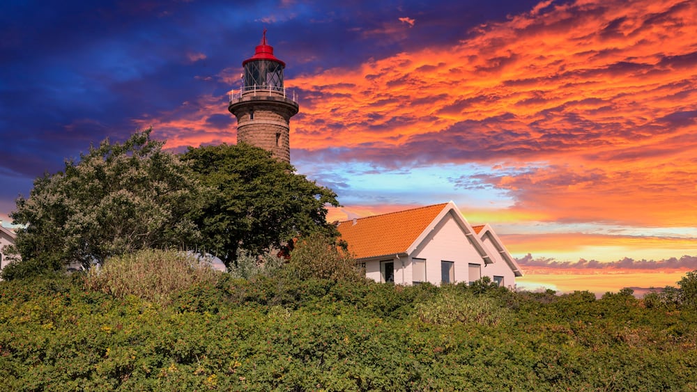 A lighthouse, a white building, and dense greenery.