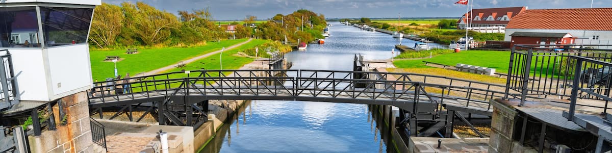 A canal with a lock system, a bridge, and a building with a red roof.