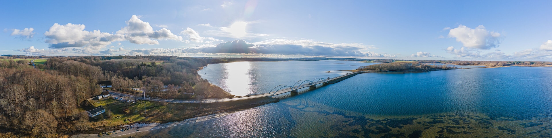 A river with a bridge, surrounded by trees and fields.