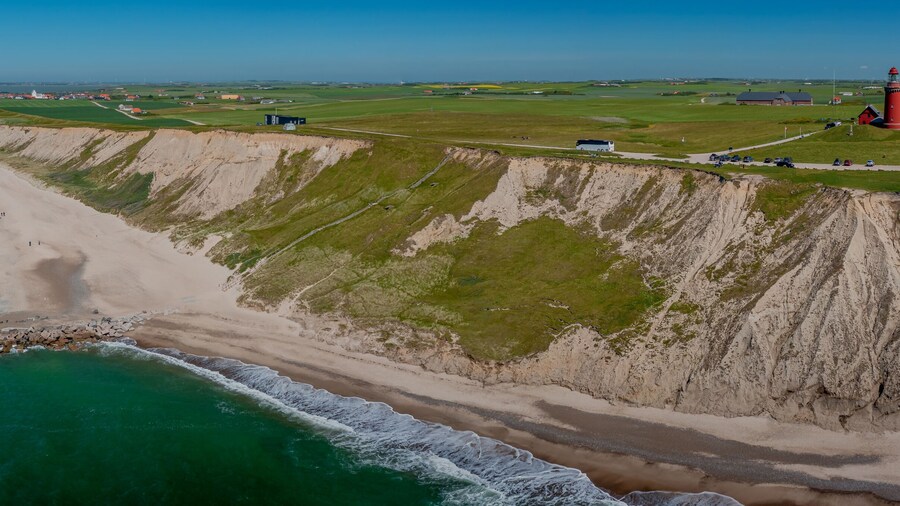 Cliffs and breakwaters on the coast of Bovbjerg Fyr at Ferring near Lemvig. View of the North Sea, lighthouse Bovbjerg Fyr and the village of Ferring with white church and Ferring Sø Fjord.