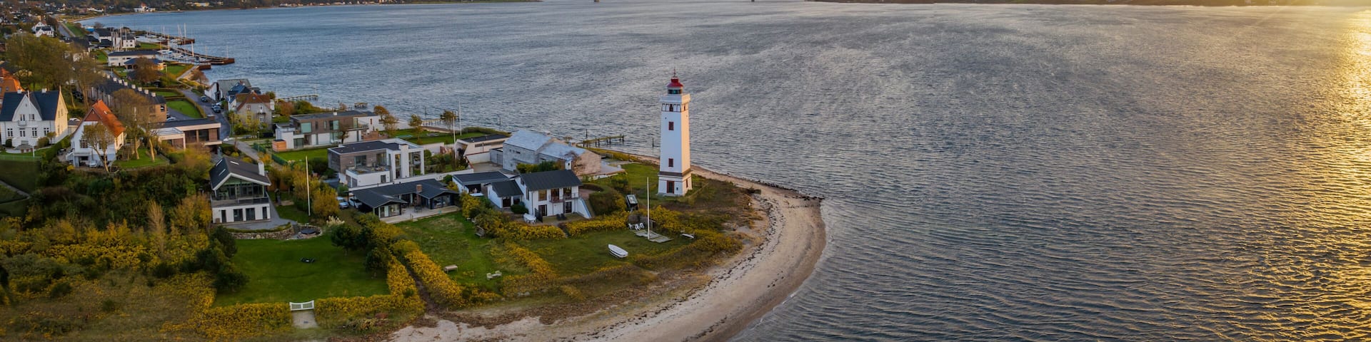 Strib Lighthouse, a picturesque historic beacon on the Danish coast, set against the backdrop of the grand Den Nye Lillebæltsbro (The New Little Belt Bridge). Lighthouse on the Beach in Middelfart.