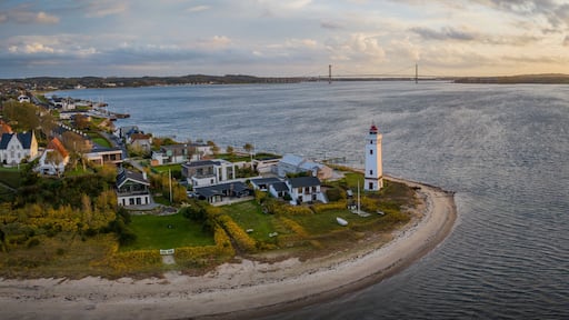 Strib Lighthouse, a picturesque historic beacon on the Danish coast, set against the backdrop of the grand Den Nye Lillebæltsbro (The New Little Belt Bridge). Lighthouse on the Beach in Middelfart.