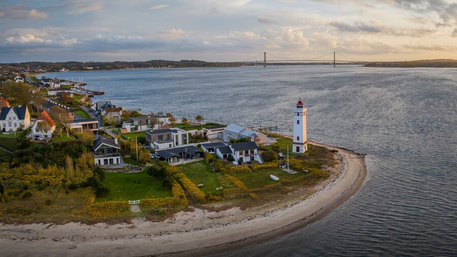 Strib Lighthouse, a picturesque historic beacon on the Danish coast, set against the backdrop of the grand Den Nye Lillebæltsbro