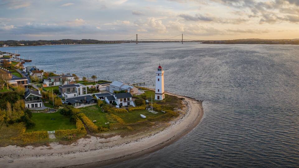 Strib Lighthouse, a picturesque historic beacon on the Danish coast, set against the backdrop of the grand Den Nye Lillebæltsbro (The New Little Belt Bridge). Lighthouse on the Beach in Middelfart.