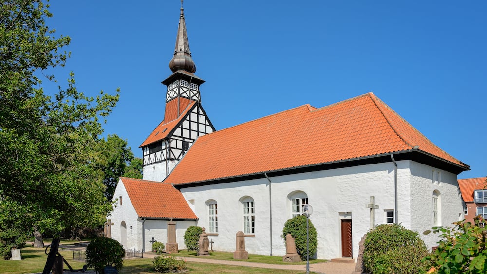 Une église avec un toit recouvert de tuiles rouges et un clocher imposant.