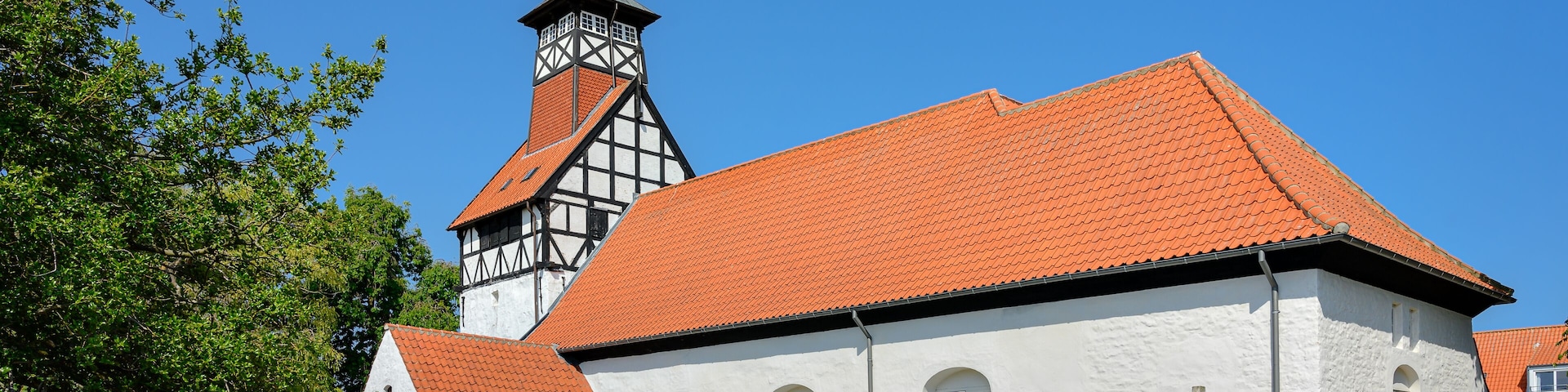 A church with a red-tiled roof and a tall steeple.