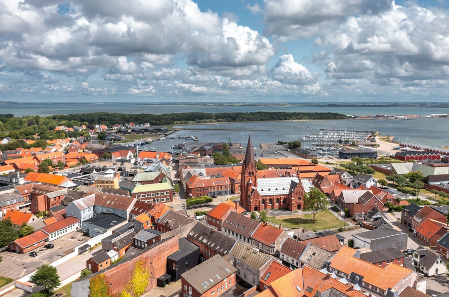 A coastal town with red-roofed buildings, a prominent church, and a marina.