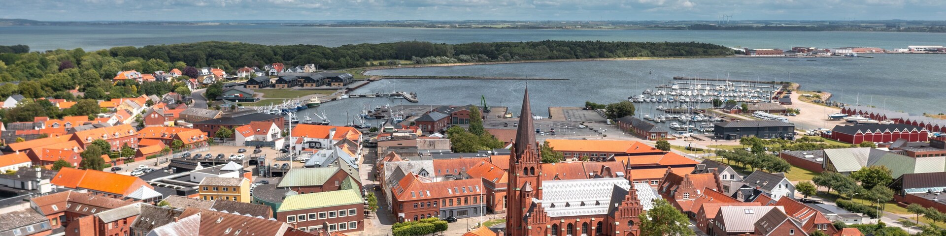 A coastal town with red-roofed buildings, a prominent church, and a marina.