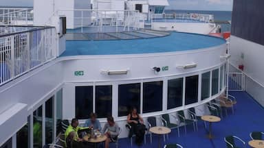 Convés de navio de cruzeiro com piscina, área de estar externa e bote salva-vidas.