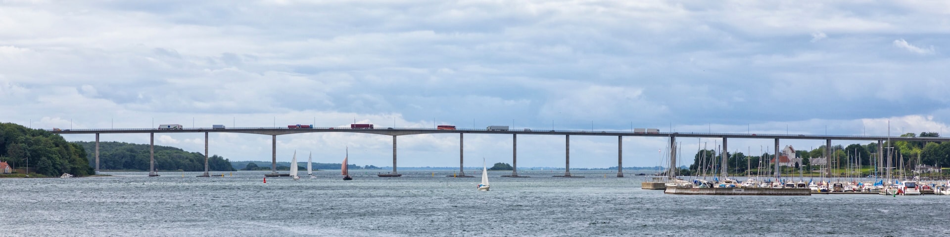 A bridge over a body of water with sailboats and a marina.