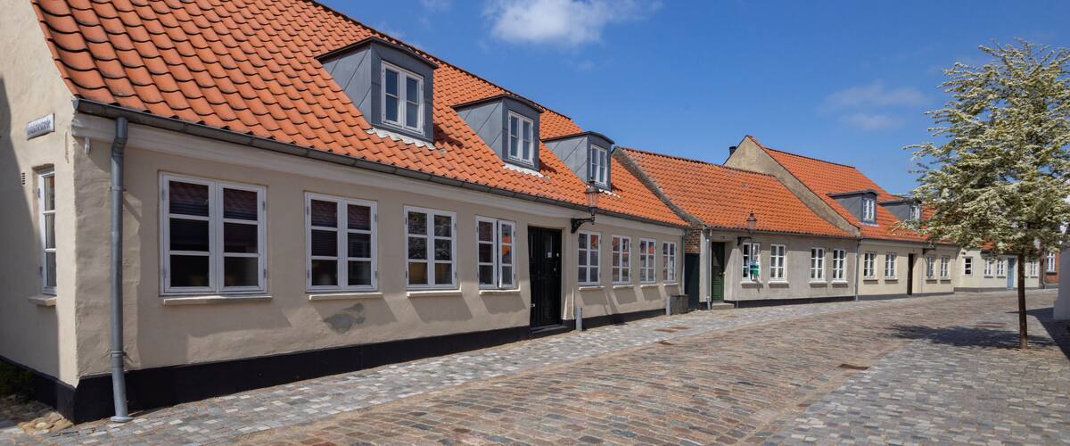 A row of traditional European buildings with red-tiled roofs and white window frames.