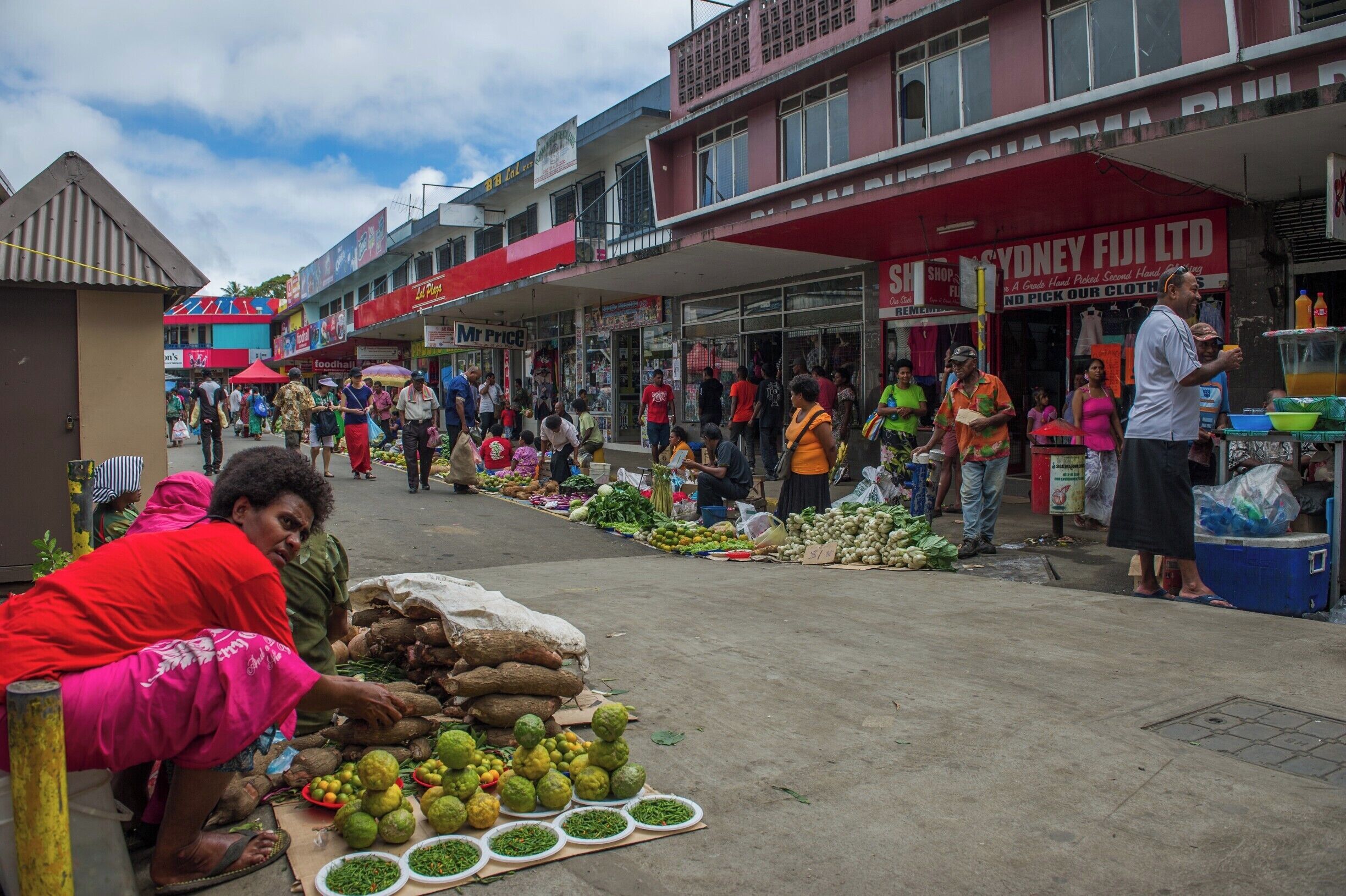 A bustling street market with vendors selling fruits and vegetables.