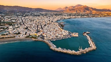 Vista aérea de una ciudad costera con un puerto prominente, rodeada de montañas.
