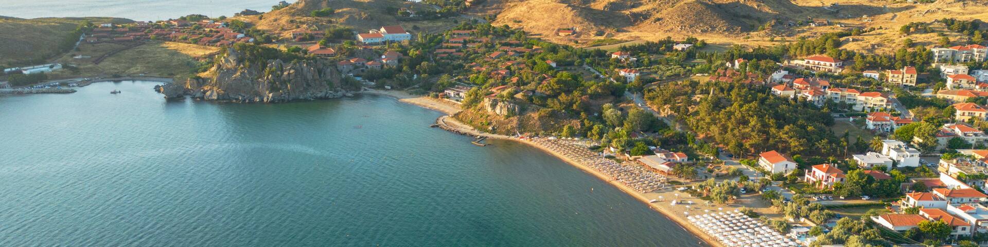 A coastal town with a beach, houses, and mountains in the background.