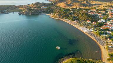 Un pueblo costero con playa, casas y montañas al fondo.